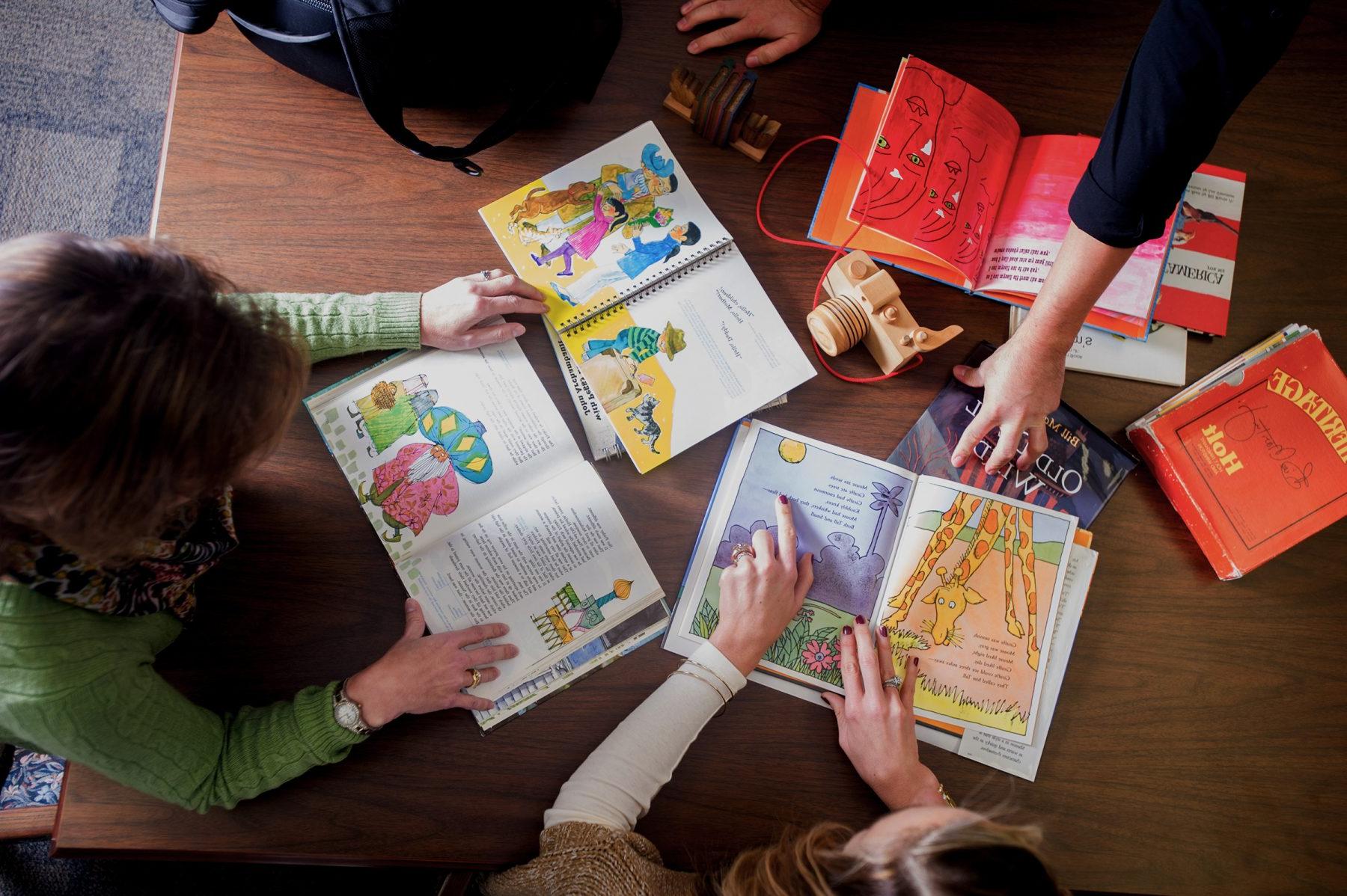 A group of educators reviewing children's book sitting down at a desk.