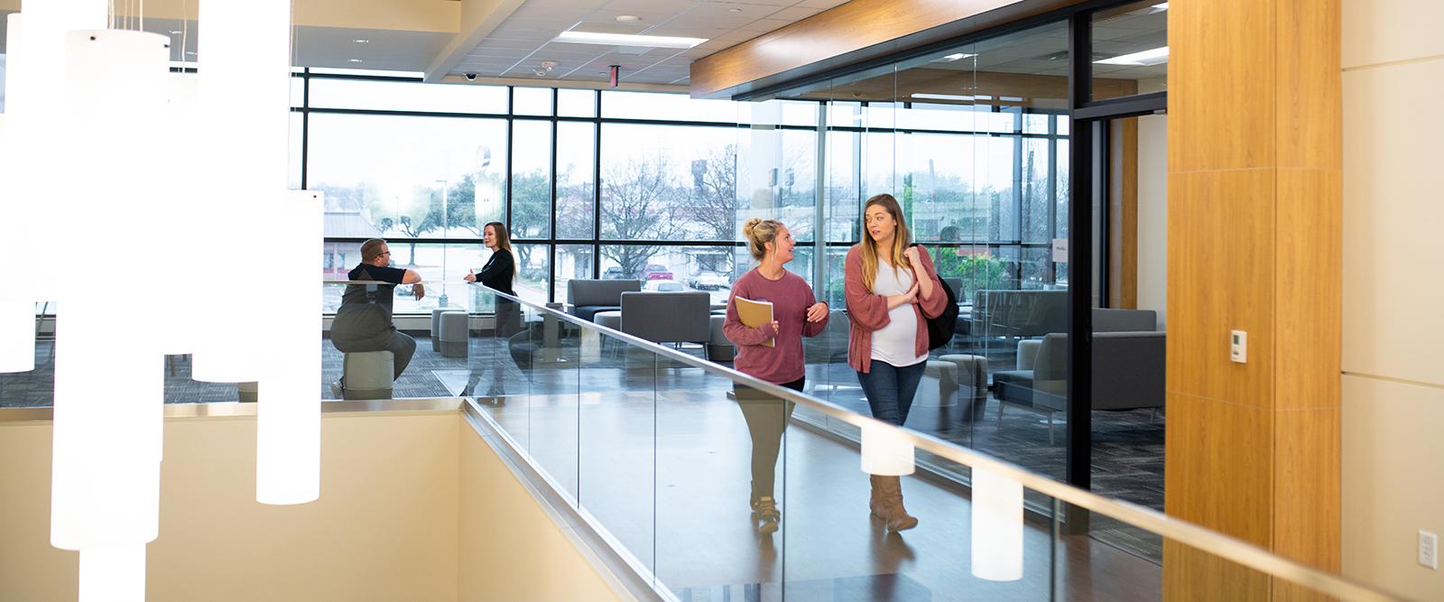 Two female students walking and talking inside the Mesquite Metroplex中心.